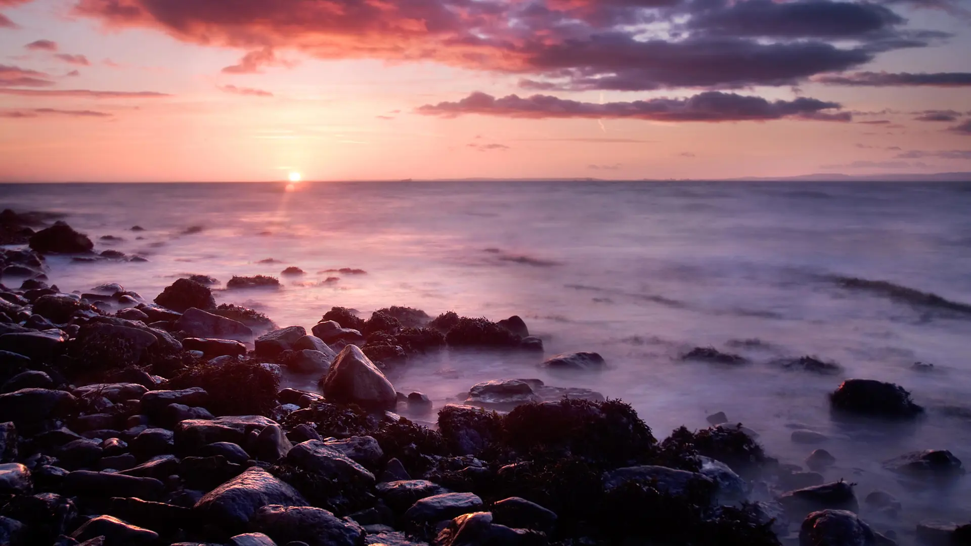 A dramatic image of a Clevedon sunset with a low fog rolling over the sea. Colours are warm oranges and purples