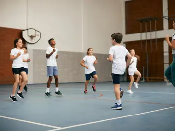 Timeout - A group of school kids running on a spot in a school gym lead by a teacher (right)